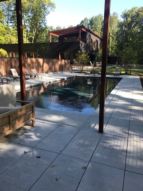 A modern cedar home with a rectangular inground pool, serviced by River Valley Pools